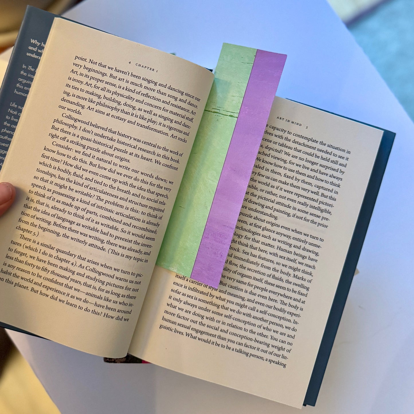 Open book with a purple and green bookmark on a light blue background.
