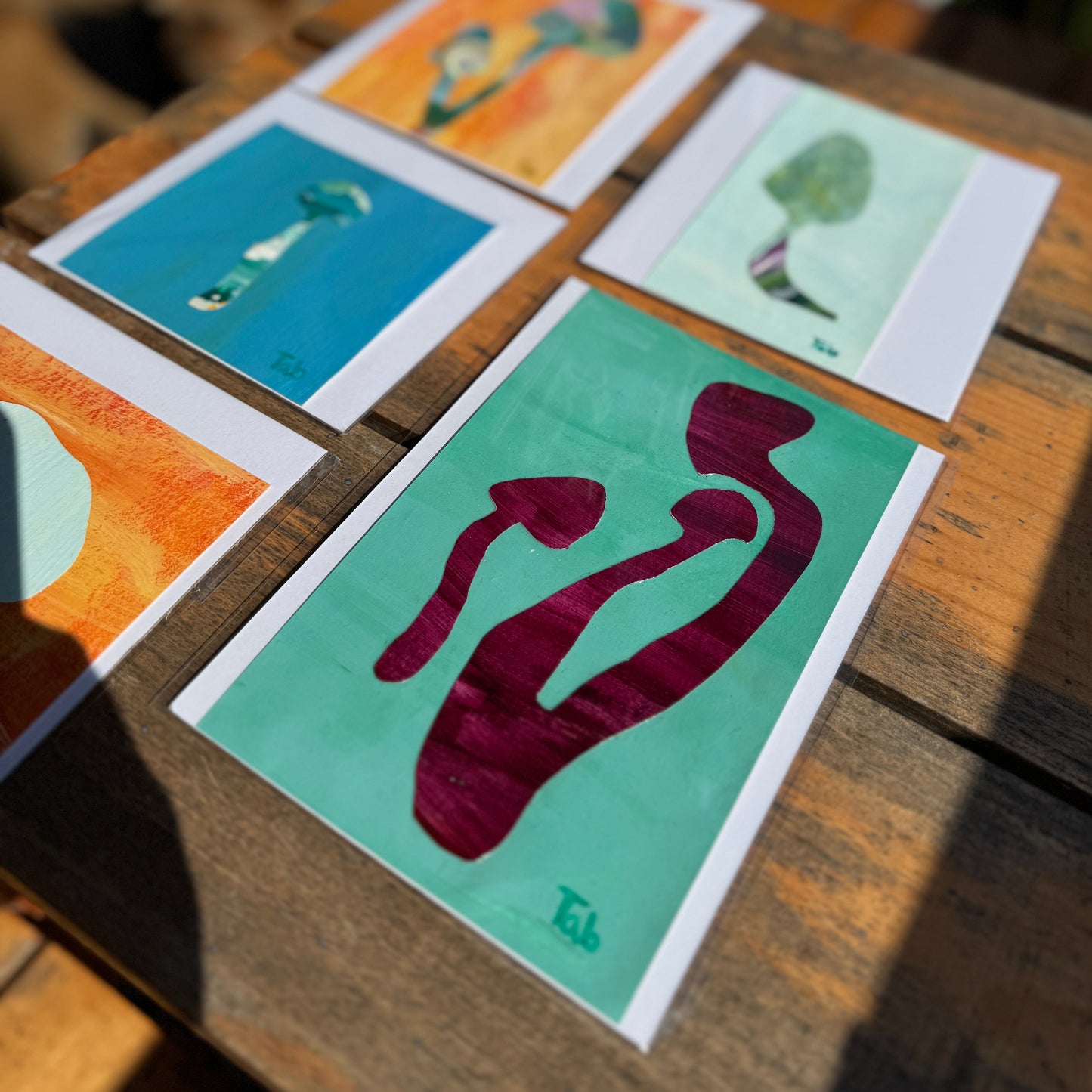 Set of small collage artworks on a wooden surface.