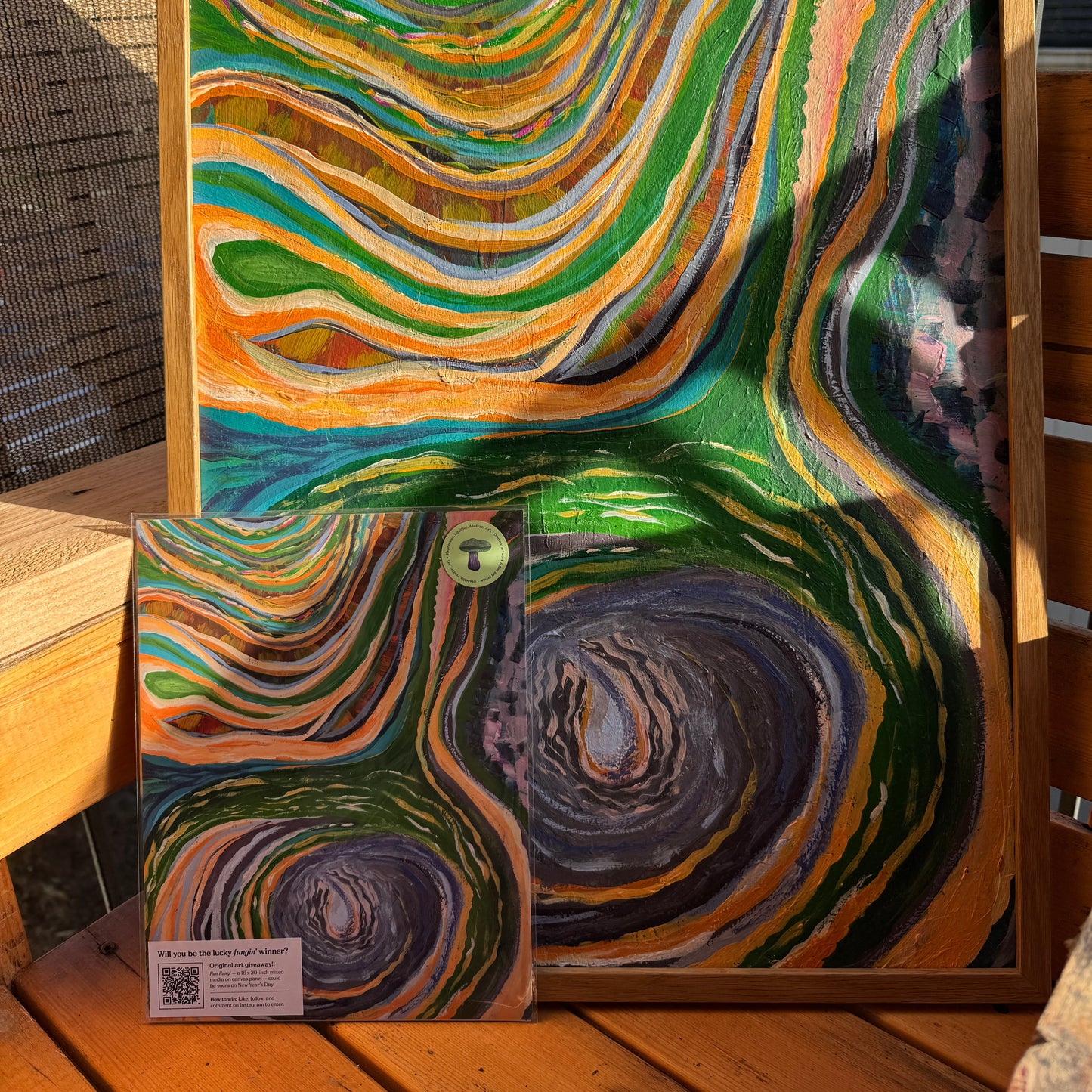 A large and small print of The Never-Ending Spiral was photographed on a wooden bench in nature.