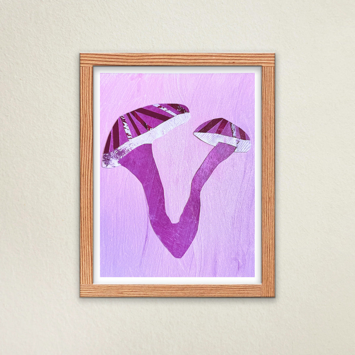 Mycelium, My Choice fine art print hanging on a wall in a wooden frame. The artwork features a pink background, white border, and a large, graphic mushroom appearing as a “V” shape. The mushroom is graphic and vibrant.