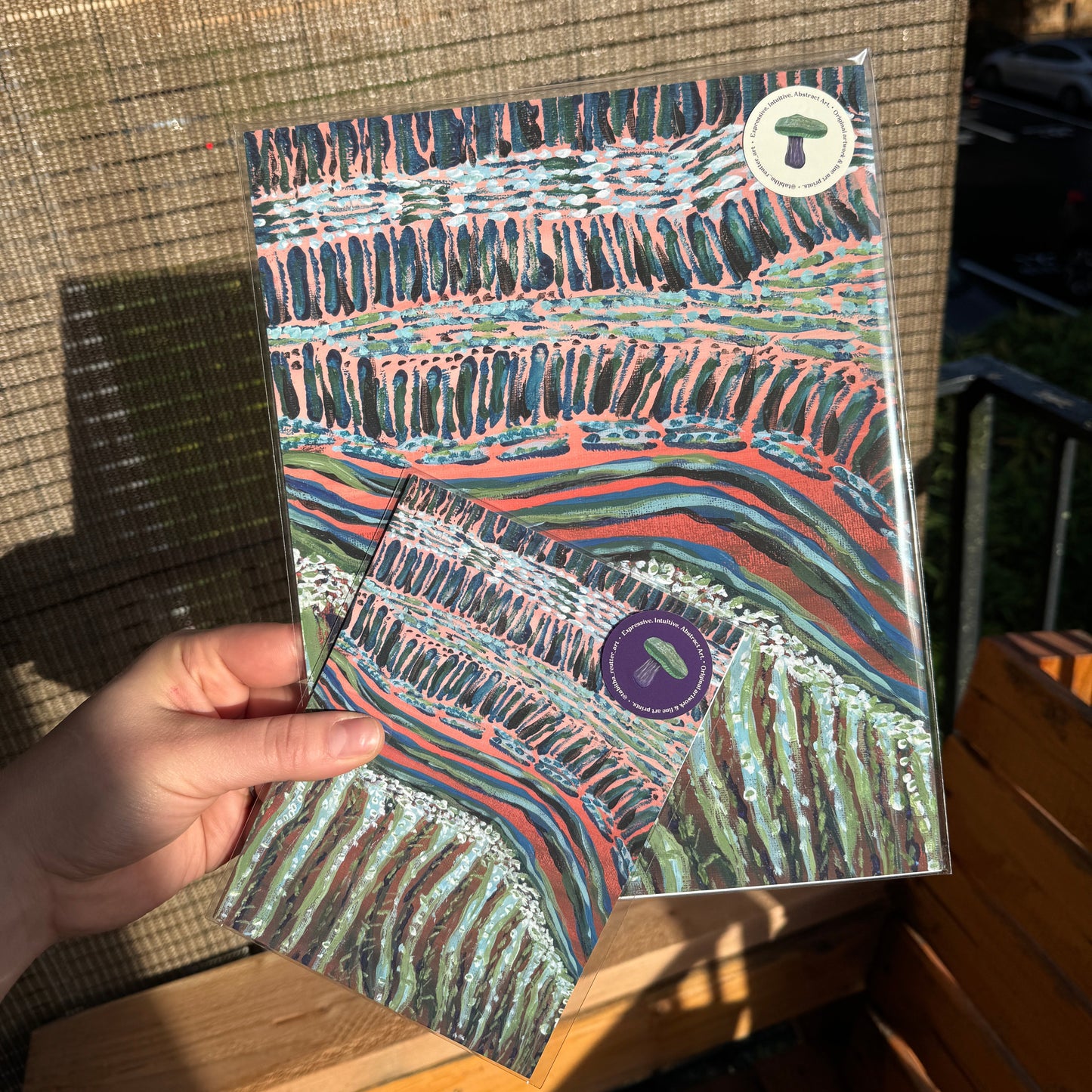 Small prints of abstract artwork, Move Along Everyone, photographed on a wooden bench.