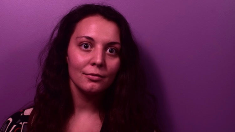 Artistic profile image of Tabitha against a radiant purple background, cropped at her shoulders. She has brown hear and large brown eyes.