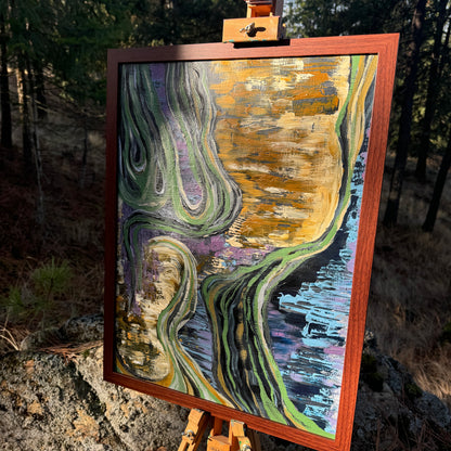 A large, earth-toned, multicolored abstract painting is shown in the woods with morning sunlight hitting it. It is displayed in a wooden frame on an artist's easel.