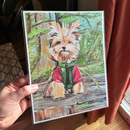 Artist holding the print in hand — featuring a cute small dog on a tree stump. 
