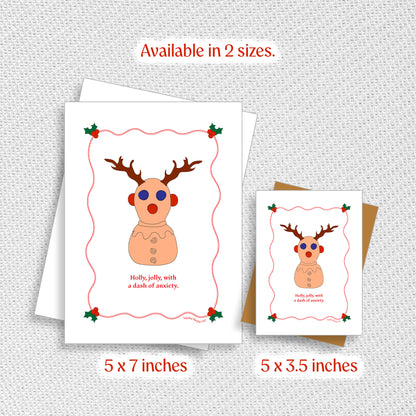 A funny ADHD Holiday card designed for the neurodivergent community. The card shows an illustration of the neurodivergent toy, Panic Pete with antlers is shown next to the phrase holly, jolly, with a dash of anxiety. A small size and large size is shown next to each other for scale.
