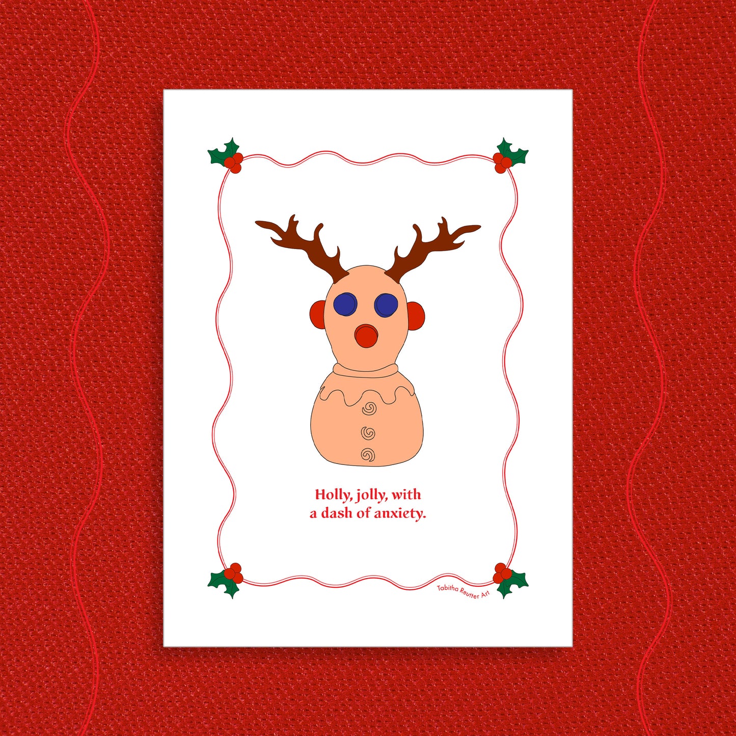 White greeting card displayed on a vibrant Holiday red felt-textured background with an illustration of the squeeze neurodivergent toy, Panic Pete, wearing festive reindeer antlers in the center of the card. Red text, under the artwork, reads: Holly, jolly, with a dash of anxiety.