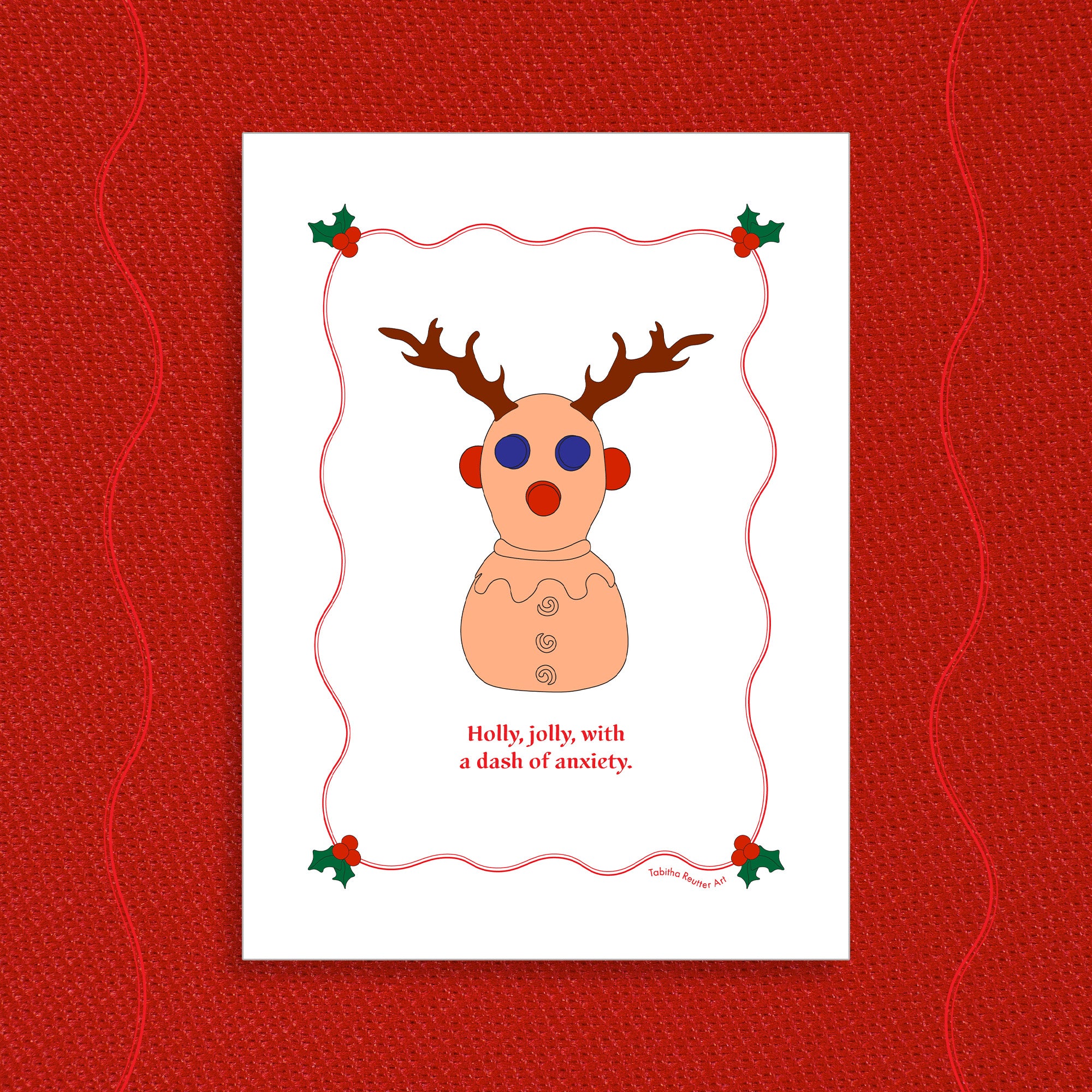 White greeting card displayed on a vibrant Holiday red felt-textured background with an illustration of the squeeze neurodivergent toy, Panic Pete, wearing festive reindeer antlers in the center of the card. Red text, under the artwork, reads: Holly, jolly, with a dash of anxiety.