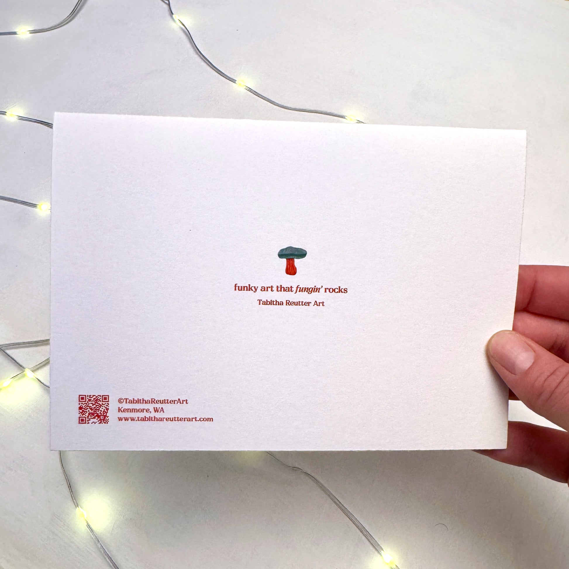 A white background with red text that reads: This holiday season support an artist" and details the artist, Tabitha Reutter, is a small business located in Seattle. She doesn't use mass production or AI in her work. Handmade only.