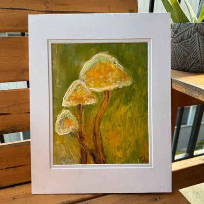 Nature-inspired, multimedia artwork, Golden Hour, on a sunny day on a wooden bench with plants. A full view of the artwork is in the white matte. 