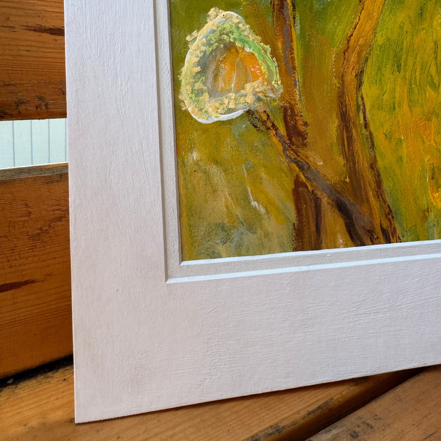 Nature-inspired, multimedia artwork, Golden Hour, on a sunny day on a wooden bench with plants. Close up of the artwork in the white matte.
