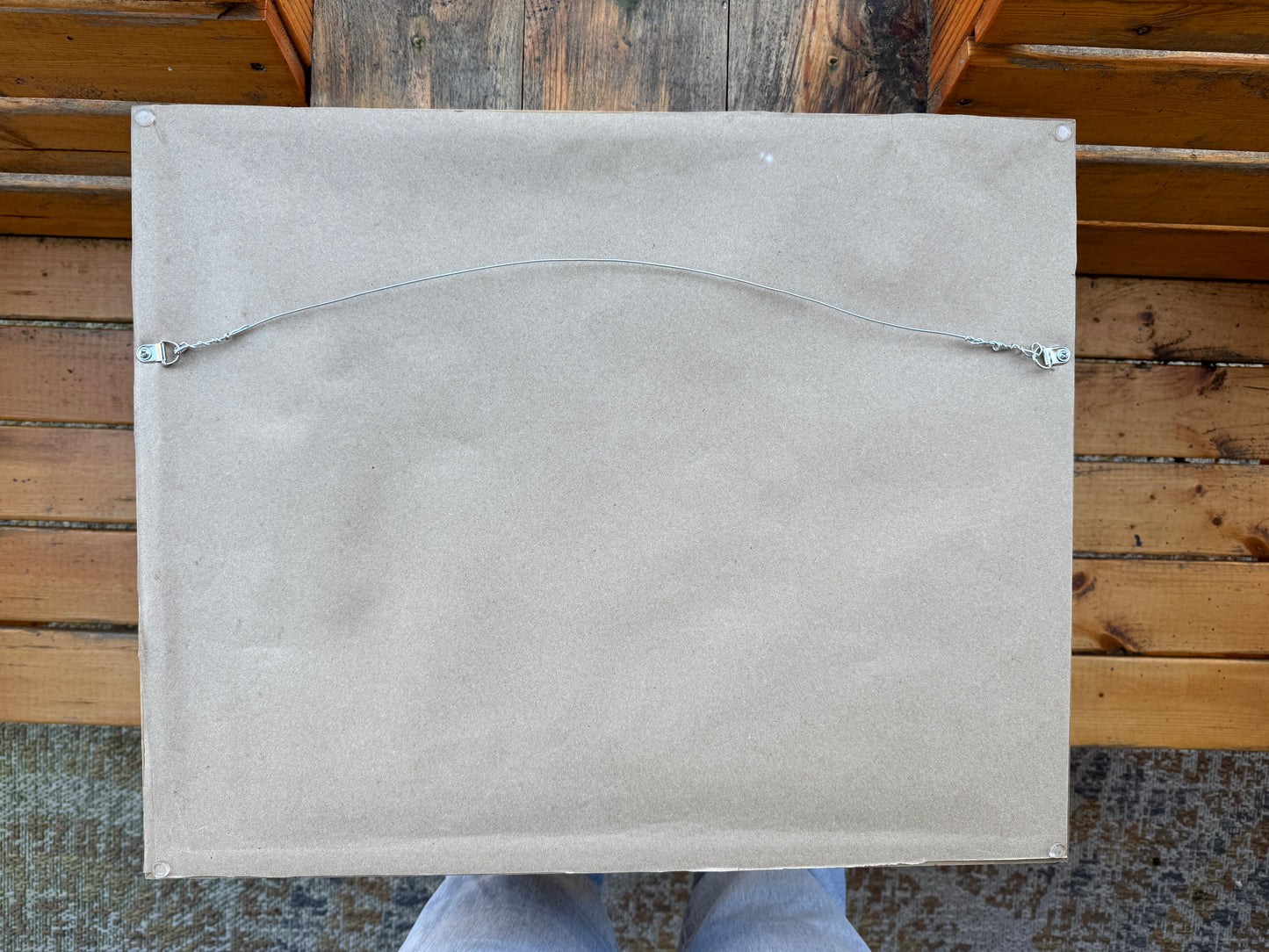 Back of artwork, Sitting With Thoughts, showing artist paper wrapped across the back of the frame. A wire rests across the back for hanging. The artwork is photographed outdoors in nature.