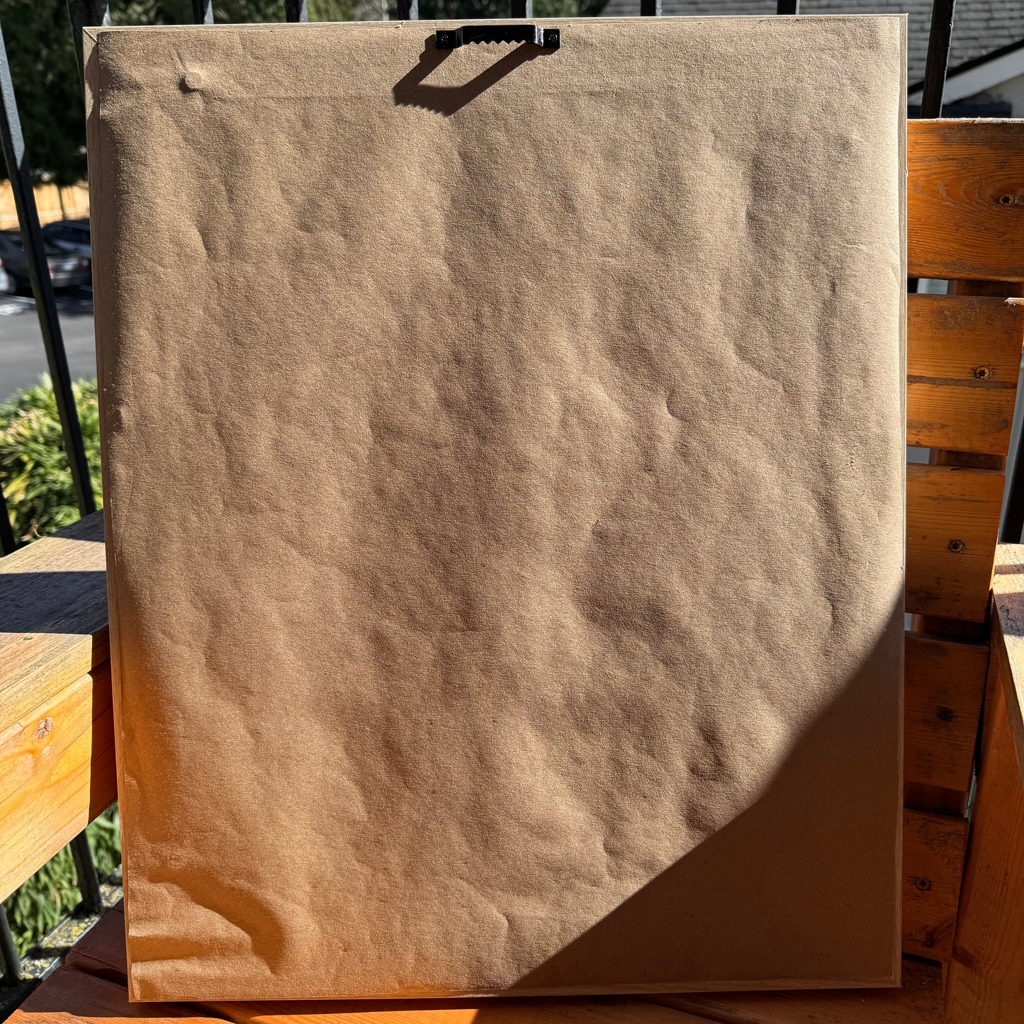 Back of artwork, Somewhere Green, showing artist paper wrapped across the back of the frame. The artwork is photographed outdoors in the sunlight.