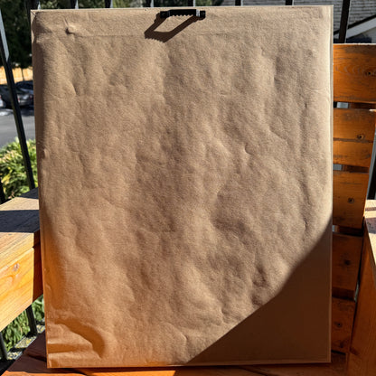 Back of artwork, Somewhere Green, showing artist paper wrapped across the back of the frame. The artwork is photographed outdoors in the sunlight.