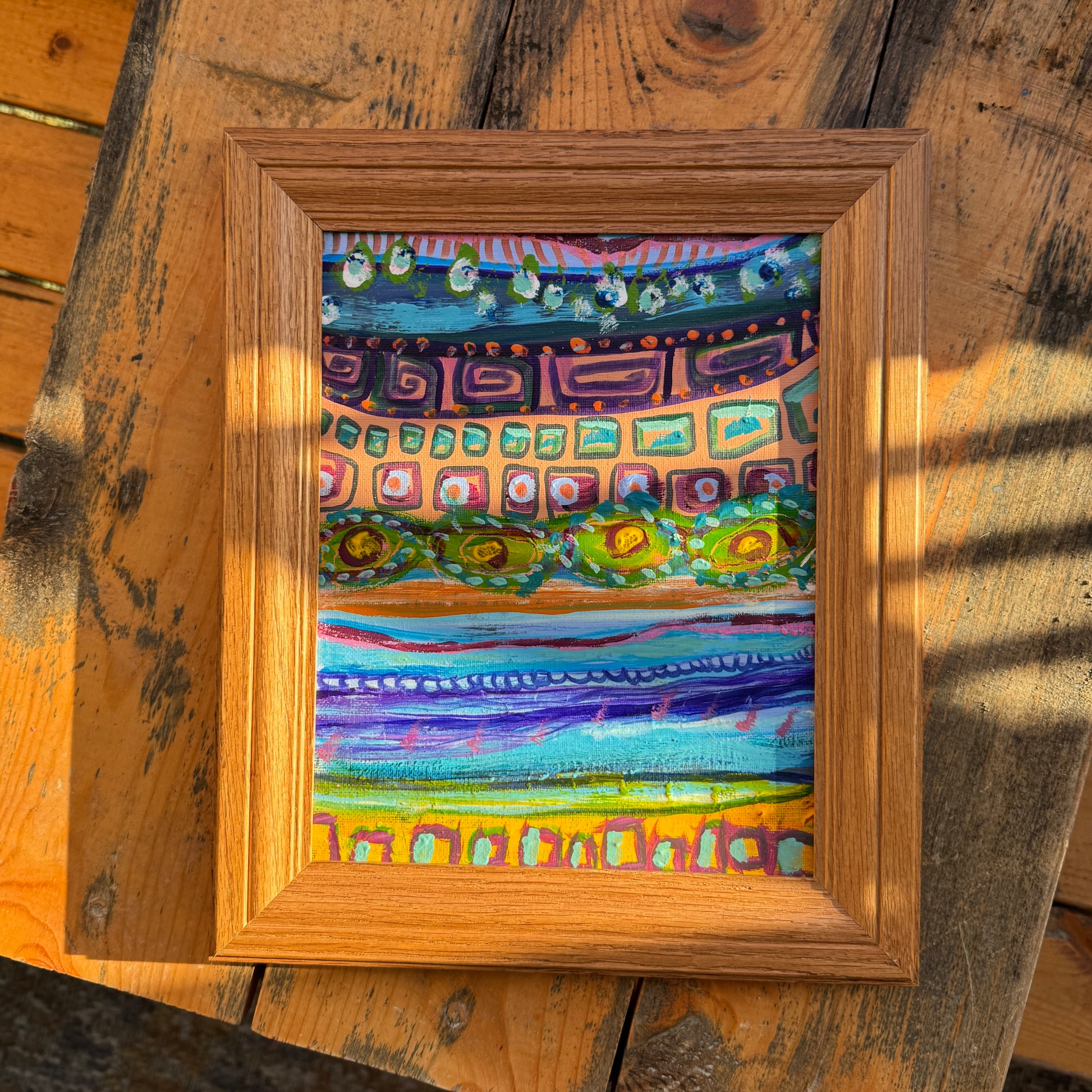 Small abstract, original multimedia artwork, Forward and Backwards, on a sunny day, resting on the top of a wooden table in nature.