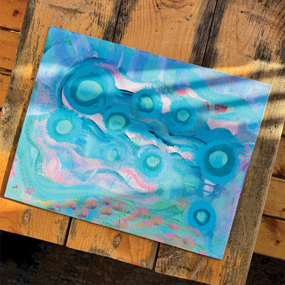Abstract artwork, Your Weird is Glowing, on a wooden bench in the sunlight. Baby blue and pink colors intermingle, creating a whimsical effect.