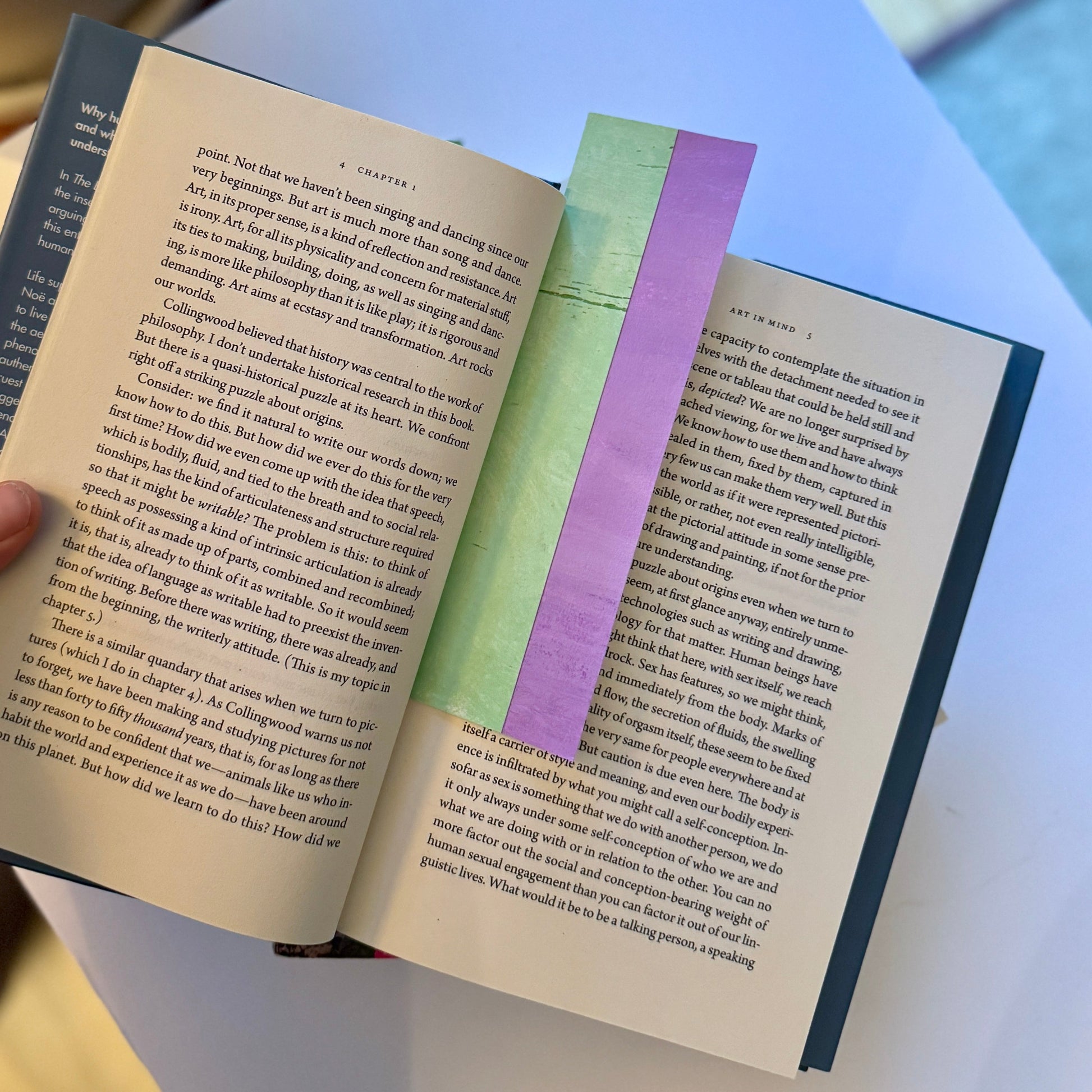 Open book with a purple and green bookmark on a light blue background.