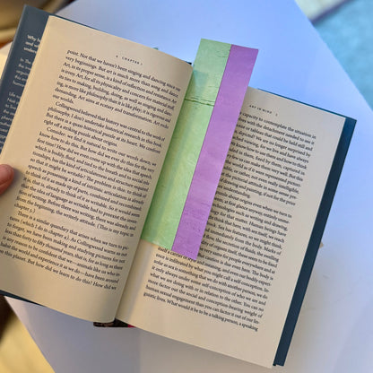 Open book with a purple and green bookmark on a light blue background.
