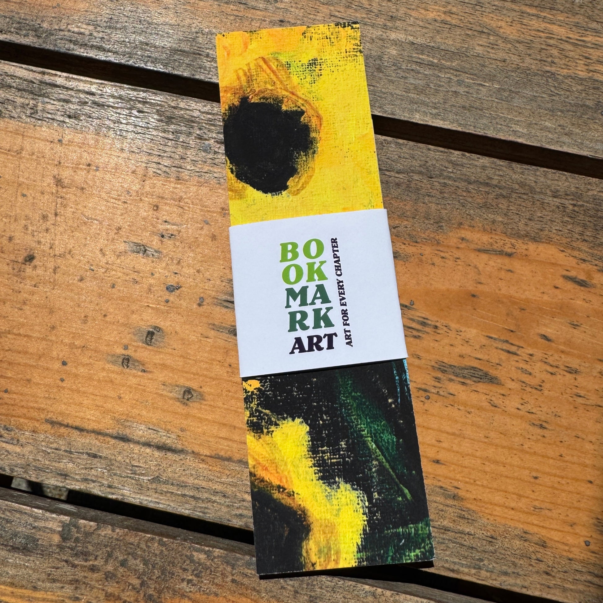 Bookmark with artistic yellow and black flower design on a wooden surface.