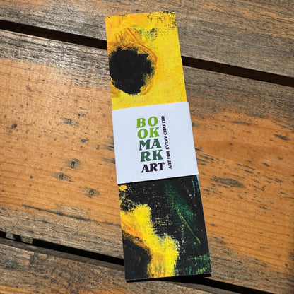 Bookmark with artistic yellow and black flower design on a wooden surface.