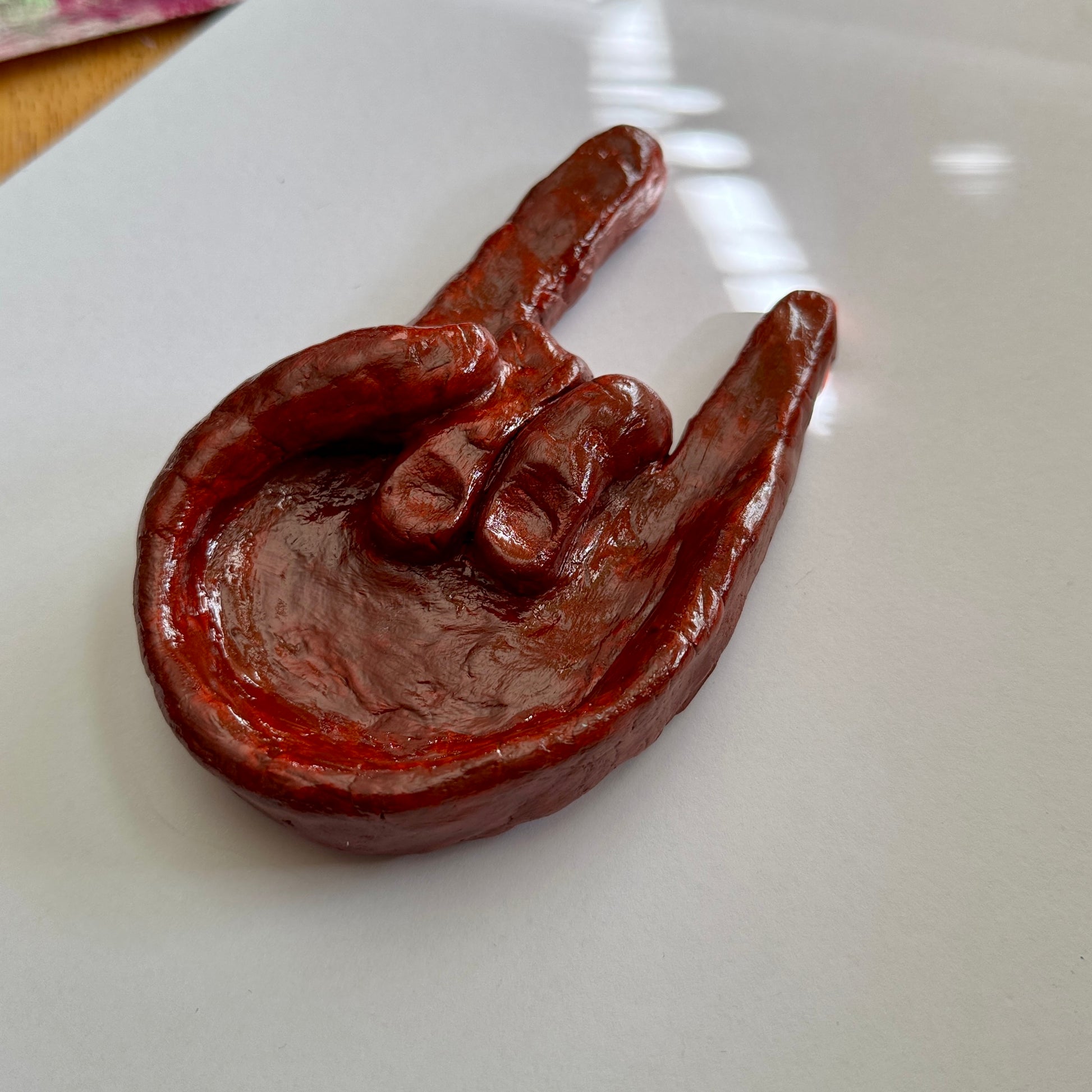Chocolate-brown rock hand dish on a white surface