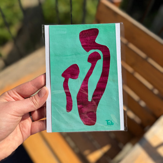 Hand holding a card with red abstract design on a green background