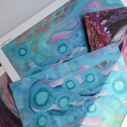 Abstract fine art prints, Your Weird is Glowing and Tunnel of Fun, are photographed artistically in the sunlight on a white background. 