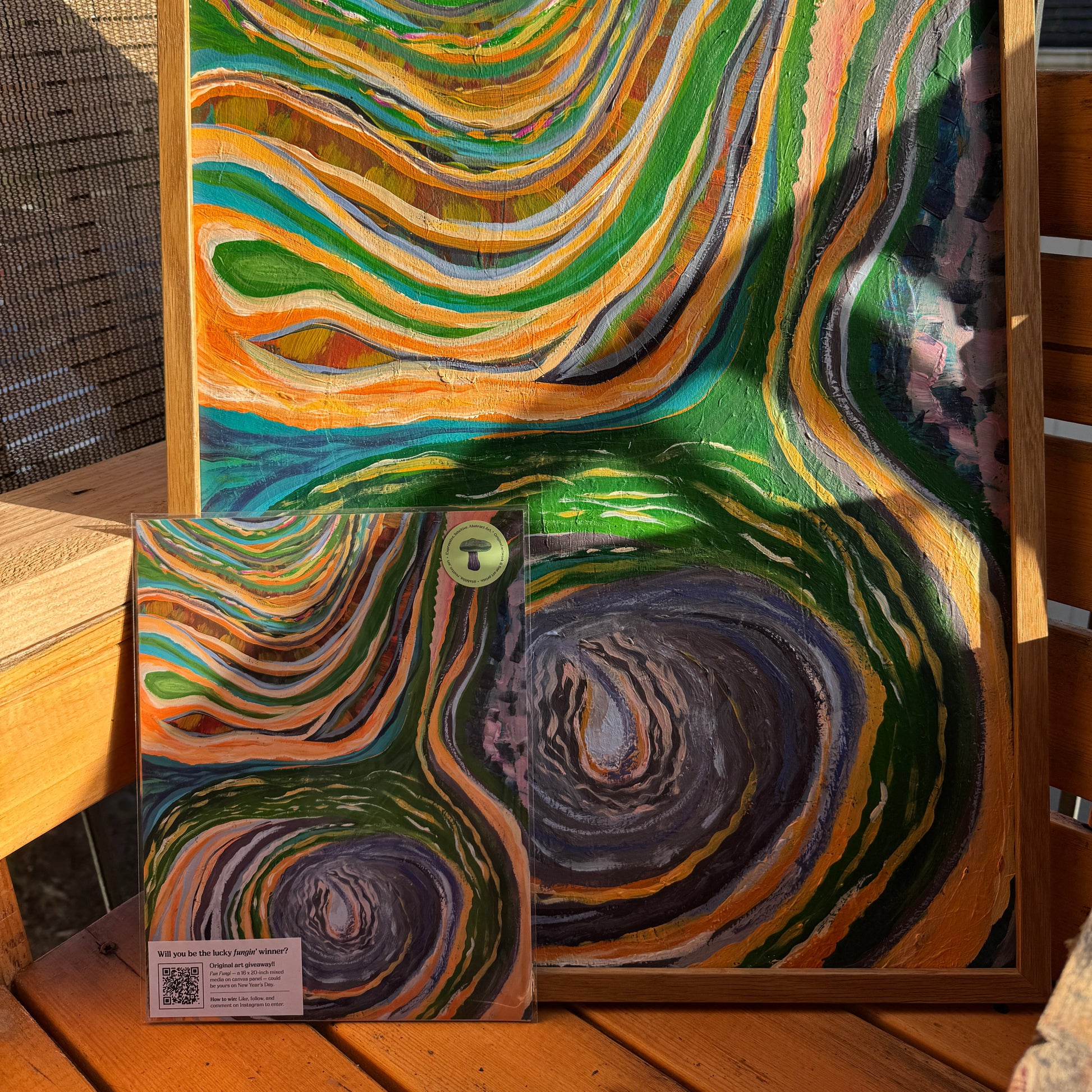 A large and small print of The Never-Ending Spiral was photographed on a wooden bench in nature.
