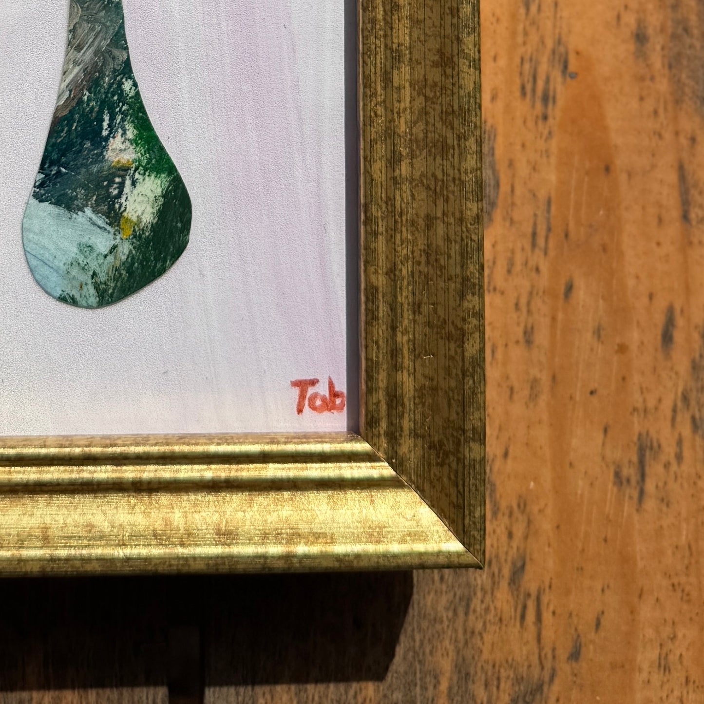 Close-up of a framed collage with a gold frame on a wooden surface.
