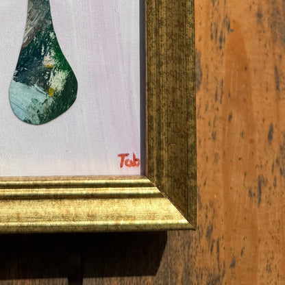 Close-up of a framed collage with a gold frame on a wooden surface.