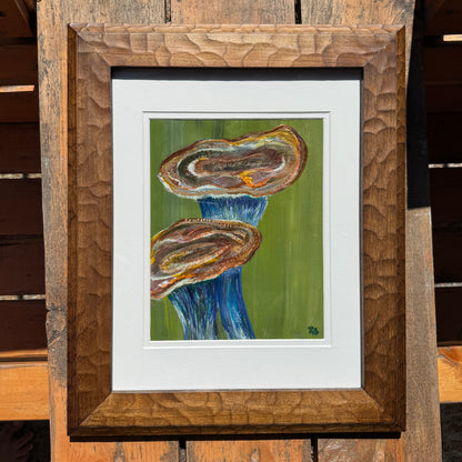 Framed artwork of an abstract blue and orange mushroom on a wooden surface