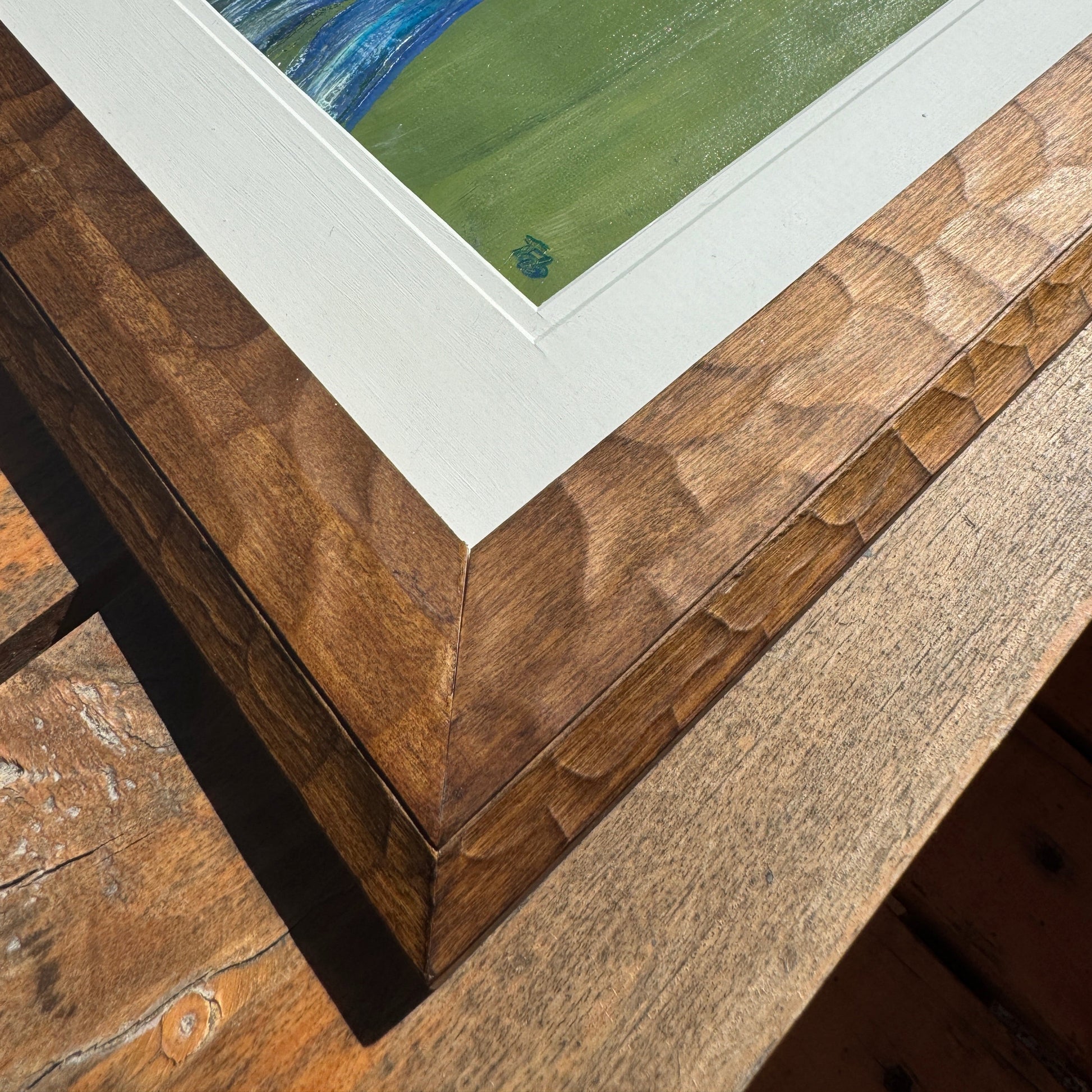 Wooden frame corner with a white mat and green artwork background