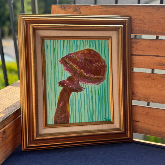 Framed painting of a mushroom on a wooden surface