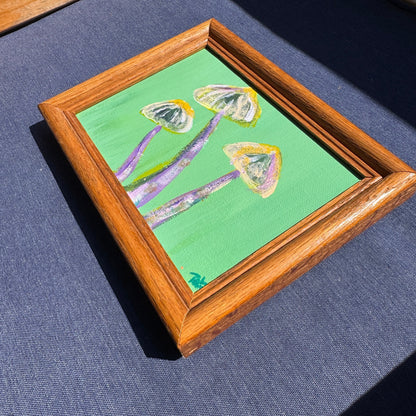 Wooden-framed painting of mushrooms on a blue background.