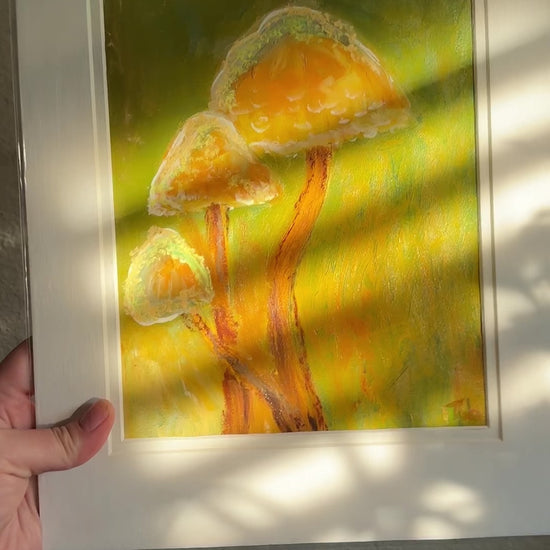 Artist holding artwork, Golden Hour, in a archival cellophane bag. The packaging is simple yet unique. The sun shines through the window, creating a beautiful glistening effect on the artwork.