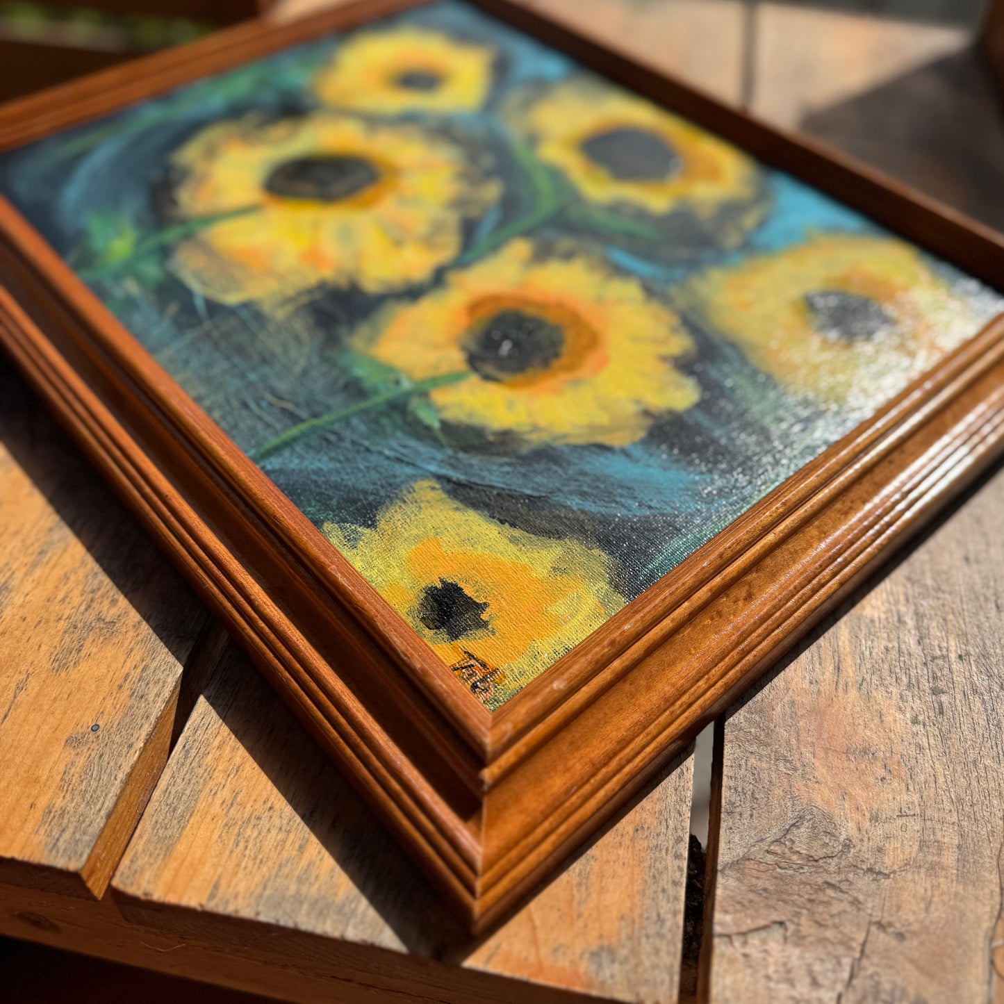 Framed artwork of sunflowers on a wooden surface