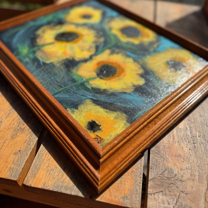 Framed artwork of sunflowers on a wooden surface