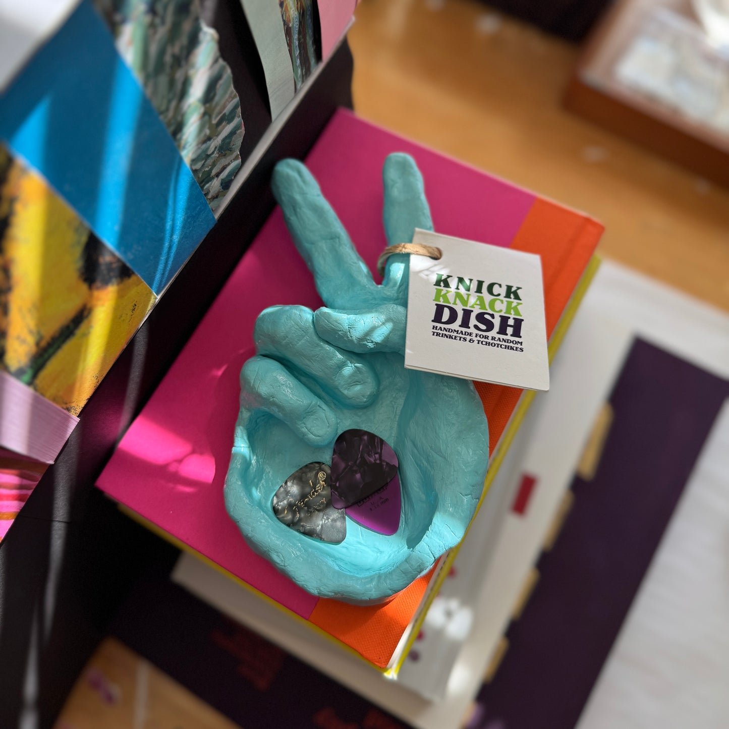 Turquoise hand-shaped dish with a tag on top of colorful books