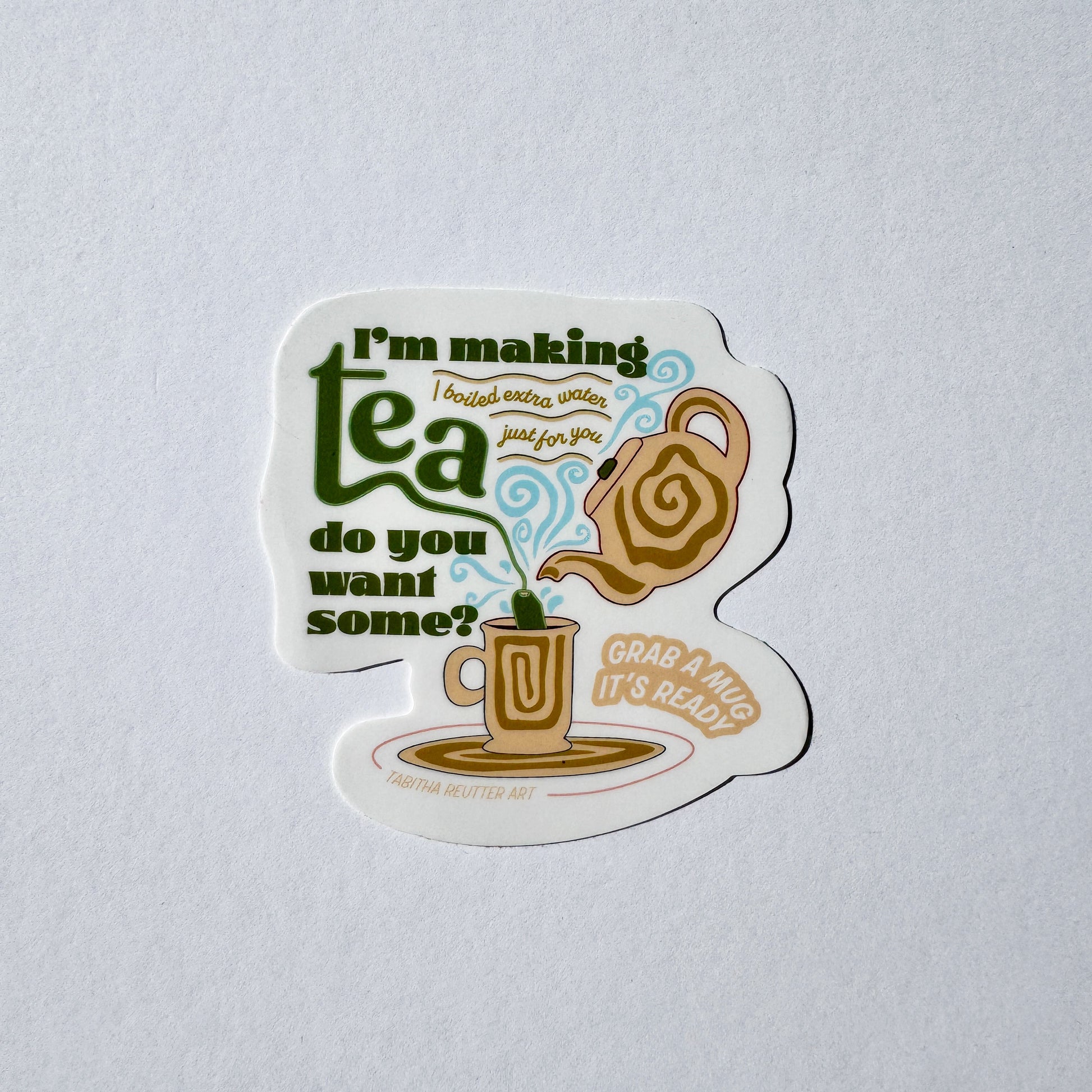Vinyl sticker of a tea kettle and mug with the text “I’m making tea, do you want some?” In bold letters. The colors are earth tones and communicate a relaxed look. Baby blue swirls layer over the image, appearing to be hot steam coming from the tea mug.